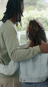 Vertical video: Starting with arm wrap, couple leaning and viewing green hills from railing, scarf