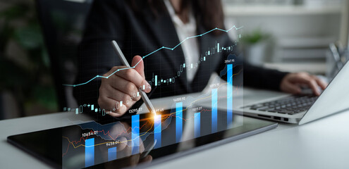 A business professional uses a tablet to analyze financial data, engaging with virtual graphs and charts, highlighting modern technology in the workplace. Scalp
