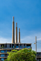 The Three Chimneys of Sant Adria de Besos: Old thermal power plant with palm trees in Barcelona, Spain. Concept of industrial heritage, urban renewal, and Mediterranean landscape