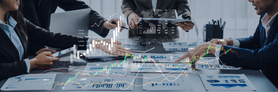 Busy business team reviews financial data and charts during a meeting. Digital graphs overlay create insight into performance and growth strategies. Scalp