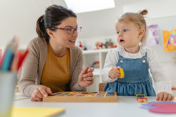 Caregiver and young girl working together on a colorful alphabet puzzle in a bright, playful classroom setting