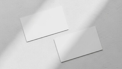 Two blank business cards casting shadows on a textured surface