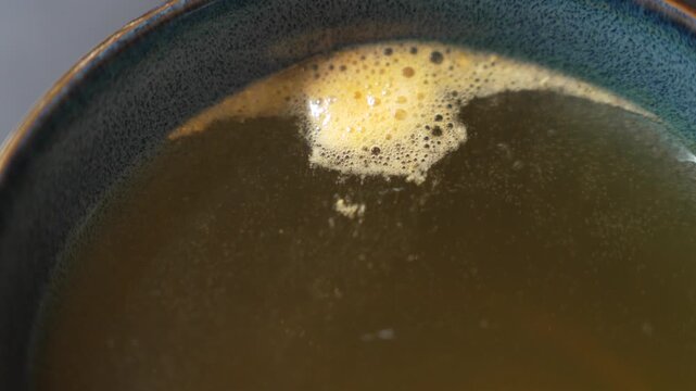Effervescent vitamin dissolving in water as rising bubbles create a foaming reaction and gradually change the liquid color in a closeup view of the dissolving supplement process.