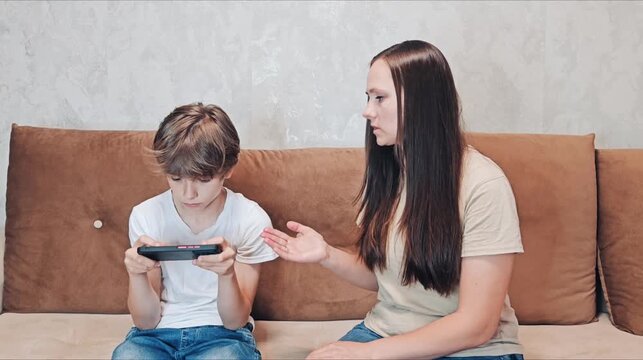 Teen addicted to smartphone ignoring mam on couch. teenage boy focused on his smartphone, ignoring mam who expressing concern or frustration. Concept screen addiction, family communication issues.
