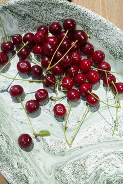 freshly picked ripe red cherries on a plate in bright natural light