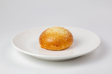 Bread roll with topping on white textured plate - appetizing baked goods on white background