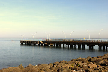 Obraz premium • Morning Serenity on the Coastal Pier A tranquil long exposure shot of a modern pier extending into the calm sea under a soft, clear morning sky. 