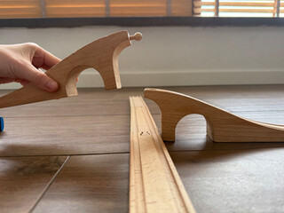 hand connecting wooden toy bridge on a brown wooden floor, copyspac concept of education,...