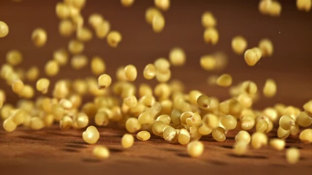 Millet groats fall on a wooden table. Filmed on a high-speed camera at 1000 fps. High quality FullHD footage