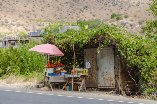 Areni, Armenia - 16 August 2025: View of a rustic roadside fruit stand, bursting with vibrant colors against the muted, arid landscape, offering a sweet respite from the journey..