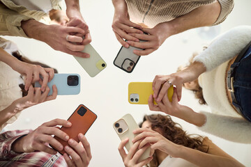People in a circle use smartphone phones together. A diverse group shares screens to boost communication, social links, and network during a meeting. Clear concept of connected teamwork.
