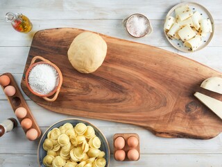 The culinary canvas unfolds to reveal a wooden board where fresh girasoli pasta nestles beside dough, flour, cheese, and eggs, ready to create an exquisite Italian feast