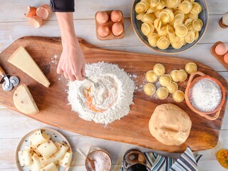 A person is skillfully blending eggs into flour on a wooden board, crafting fresh pasta dough....
