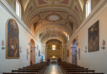 The austere interior of the Propositura di San Lorenzo, Campiglia Marittima. Its simple, single-nave Romanesque structure is adorned with frescoes and a painted truss ceiling, Tuscany, Italy