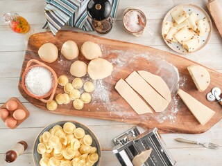 On a rustic wooden board, fresh pasta is lovingly prepared. Girasoli are taking shape beside flour, eggs, and cheese. A pasta machine stands ready, promising a delicious culinary journey
