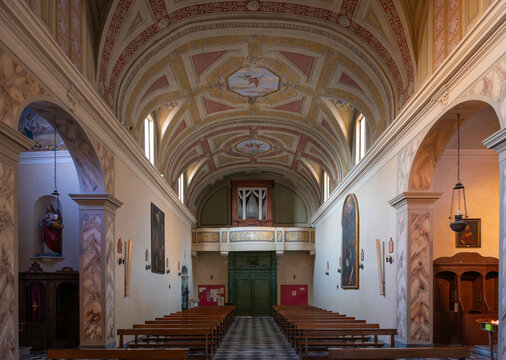 The austere interior of the Propositura di San Lorenzo, Campiglia Marittima. Its simple, single-nave Romanesque structure is adorned with frescoes and a painted truss ceiling, Tuscany, Italy