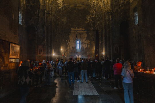 Tatev, Armenia - 17 August 2025: View of a solemn gathering inside Tatev Monastery, where soft candlelight dances on ancient stone, illuminating faces in hushed reverence.