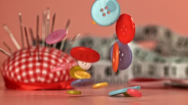 Multi-colored sewing buttons fall on a red table. Filmed on a high-speed camera at 1000 fps. High quality FullHD footage