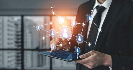 A business professional engages with a digital network on a tablet, symbolizing innovation and collaboration in a modern office environment. Tessel