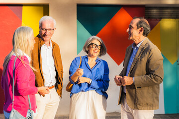 Group of seniors laughing and talking together against a colorful wall building