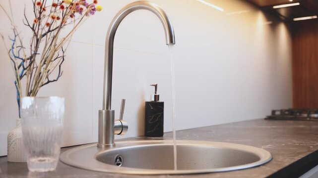 close-up shot person hand using faucet opening tap with wateropening, closing water flow tap and filling sink with water. Water running from chrome faucet. Bathroom plumbing. Using water resources. 4k