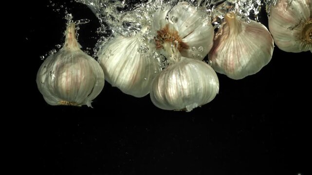 The heads of fresh garlic fall under the water. Filmed on a high-speed camera at 1000 fps. High quality FullHD footage