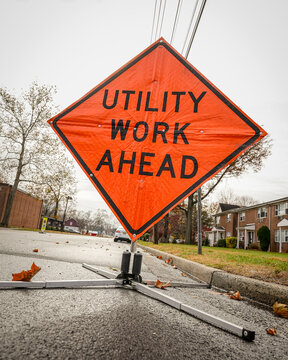 Orange construction site sign reading utility work ahead