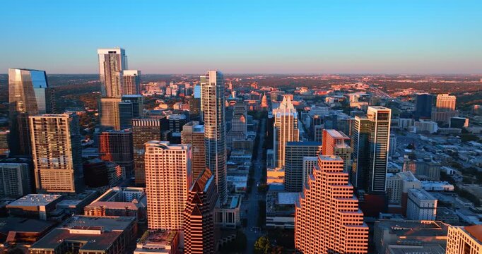 Slow movement over the long straight street in the downtown of Austin, Texas, USA. Bright setting sun lights the city panorama.