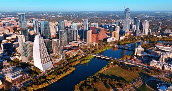 Bright sun lights the downtown of Austin, Texas, USA. Drone footage approaching the green waterfronts of the Colorado River.
