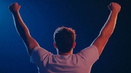 A back view of a man with arms raised in victory exuding excitement and joy representing the moment of winning against a dark blue background
