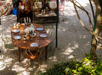 Wooden outdoor table in a garden courtyard set with vintage plates