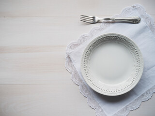 Elegant white plate setting with vintage fork on delicate doily creates a charming presentation for culinary artistry and stylish dining concepts