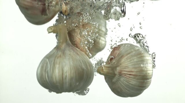 The heads of fresh garlic fall under the water. Filmed on a high-speed camera at 1000 fps. High quality FullHD footage