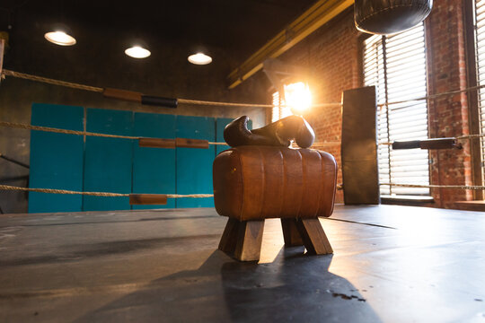 Boxing gloves lying down on boxing ring in empty gym. Equipment for fight training competition black protective boxing gloves ready for fighter winner on ring. Strength fit body workout training
