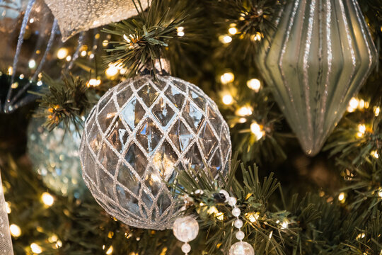 Blue lattice ornament on Christmas tree with warm festive lights and shimmering winter decor.