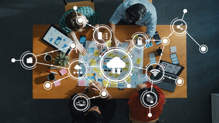 Aerial view of a team engaged in computing discussion while surrounded by digital cloud technology icons, showcasing teamwork and innovation in a modern workspace. Amity