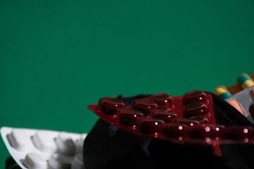 Red pill pack laying in front green background