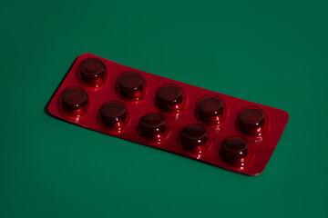 Red pill tablet laying on green background