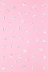 Christmas, New Year cozy pastel pink background with white snowflakes. Winter holidays concept. Flat lay, copy space. Perfect for holiday greetings, vertical banners, social media.