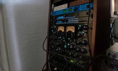 Rack-mounted vintage audio processing equipment with VU meters and analog controls. Shot with anamorphic lens.