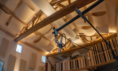 Professional boom microphone mount with studio ceiling and acoustic treatment visible. Shot with anamorphic lens. © Victor