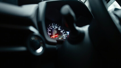 Close-up view of a car dashboard with speedometer and control knobs, showcasing modern automotive...