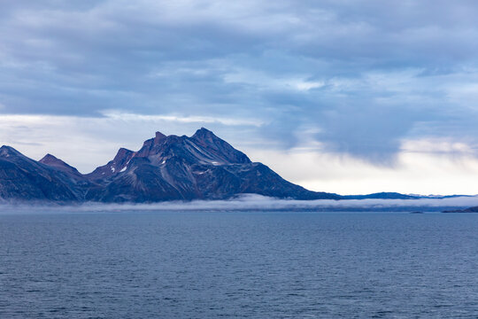 View of Mountains in Greenland from a cruise ship on the Labrador Sea near Ivittuut on the west coast at Dusk, The Blue Hour, with an Incoming Storm 
