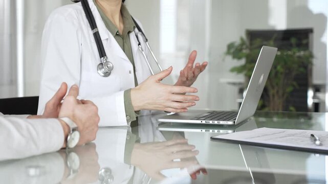 Doctor woman discussing medical information with man patient using laptop during consultation, explaining diagnosis and treatment plan, close up. Medicine, healthcare and science concept