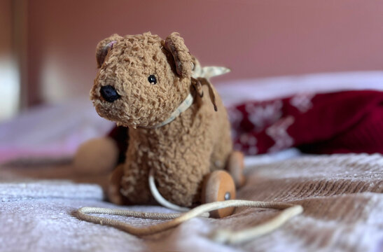 Retro Classic Vintage Nostalgic Old Plush soft Teddy Bear on Wood Wheels Toy with pull rope string attached. The toy looks as our grandparents plaid with.
