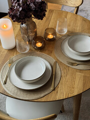 Wooden round table setting with glassware and vase creating a stylish evening atmosphere