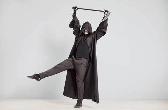 Terrible grim reaper, holding a scythe, dancing at a Halloween party on a grey background. Skeleton mask and captures the devilish, horror and death filled atmosphere of the celebration.
