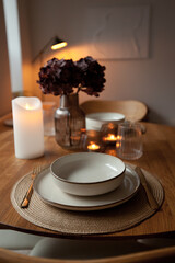 Wooden round table setting with glassware and vase creating a stylish evening atmosphere