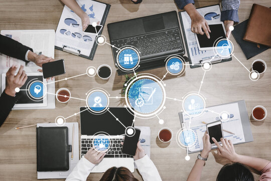 A diverse business team collaborates in a modern office, using laptops and mobile devices to analyze data, share ideas, and strategize for future projects. Tessel