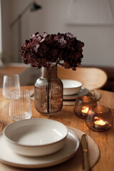 Wooden round table setting with glassware and vase creating a stylish evening atmosphere